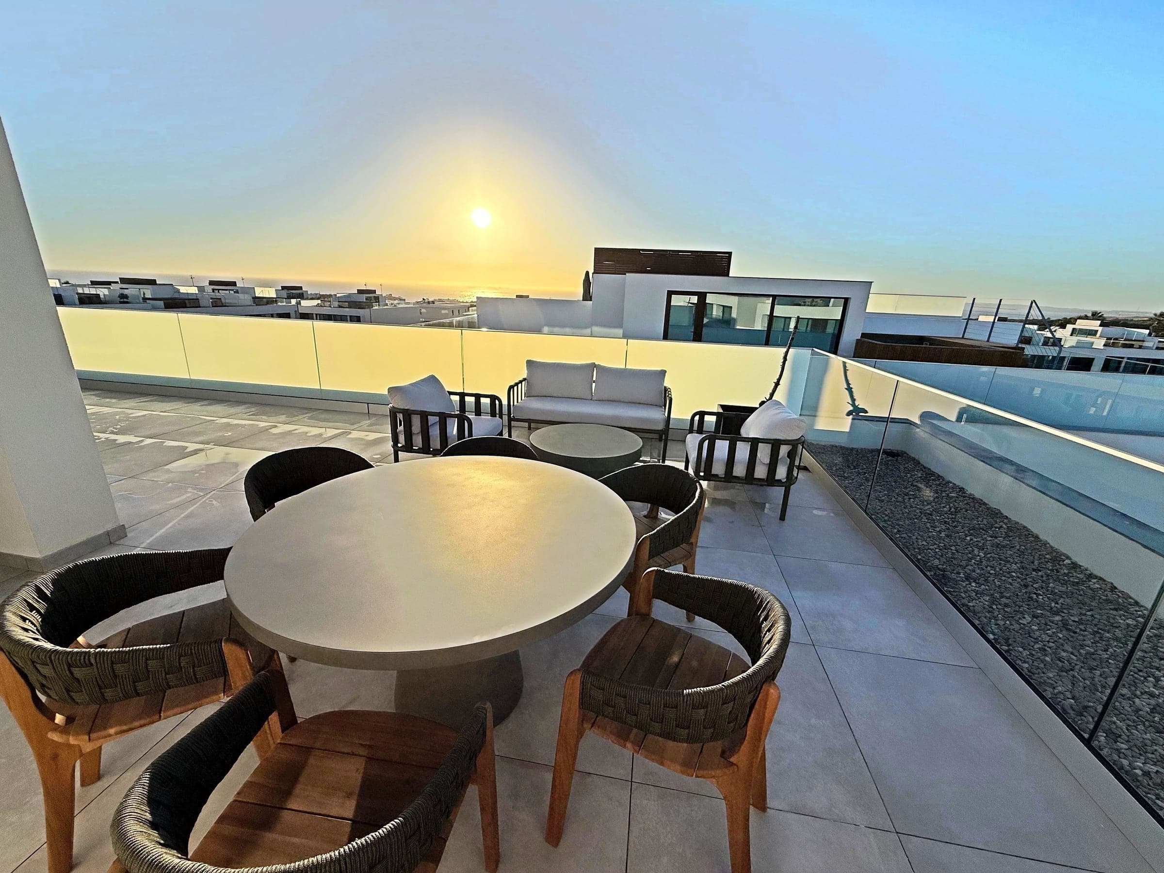 The private terrace at Blue Cove set with a dining table for six as the sun drops to the sea