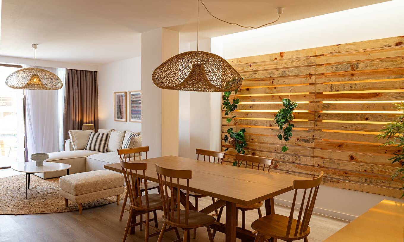 Open-plan dining area with a solid oak table, spindle chairs and a backlit wood-slat feature wall
