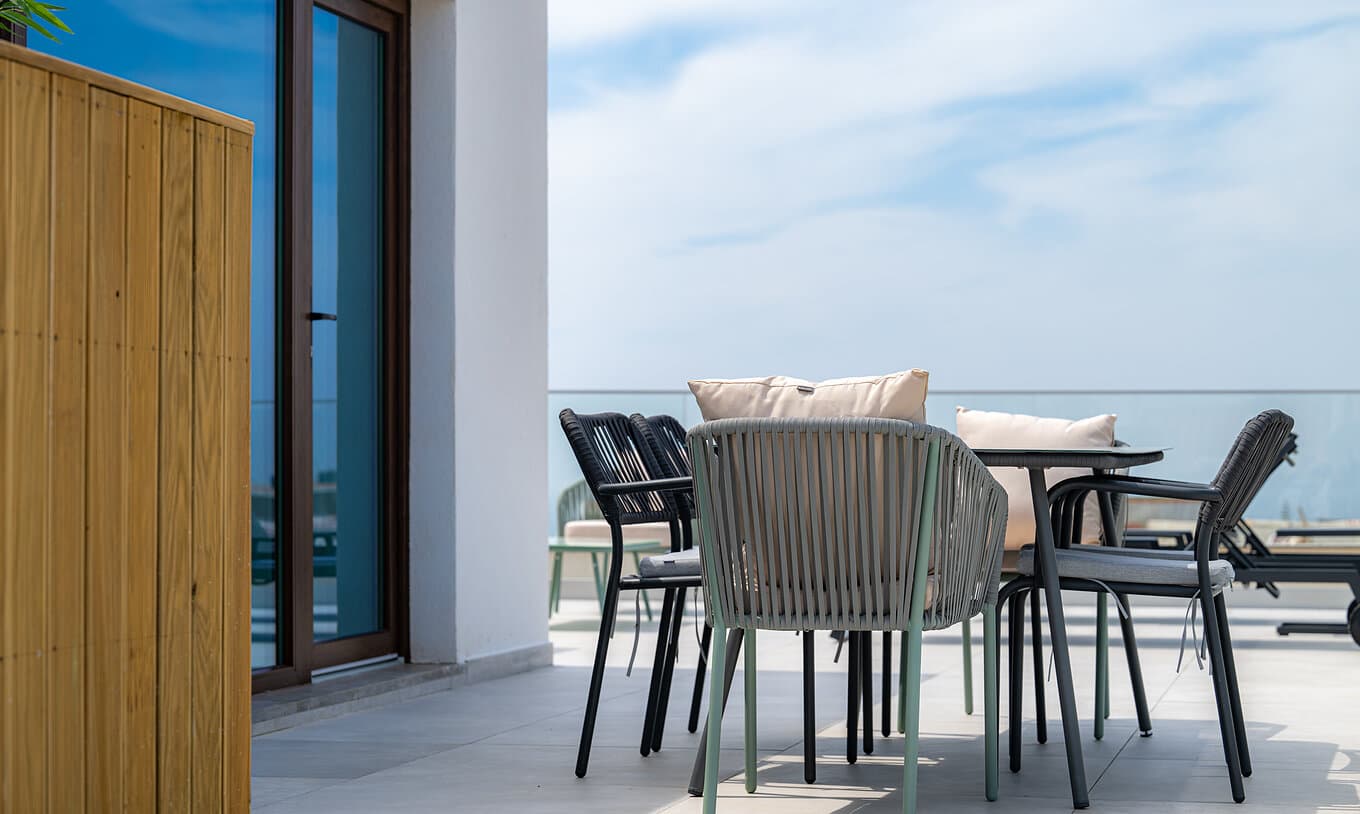 Private terrace with woven outdoor chairs and a table against an open sky