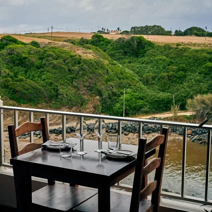 A table laid on the balcony at Lamelas, above the green scrub and the water