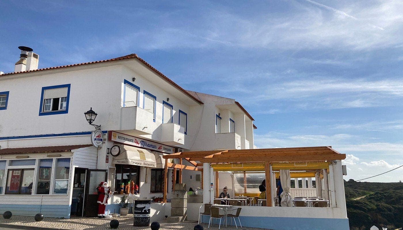 Restaurante Miramar's white and blue frontage above the coast, terrace to one side