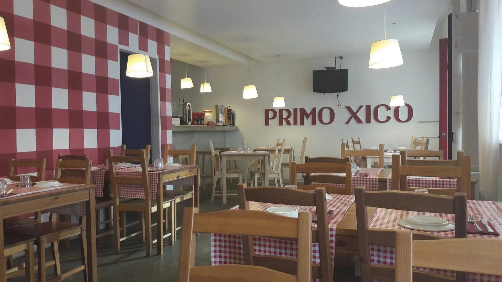 The dining room at Primo Xico, red gingham cloths and the name painted on the back wall