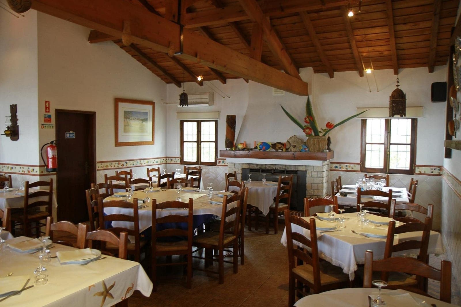 The dining room at Restaurante do Luís, tables set beneath an open timber roof