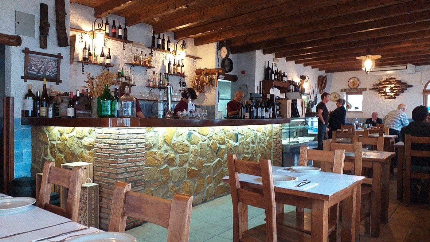 The dining room at Zé Inácio, a stone-fronted bar hung with bottles beneath a beamed ceiling