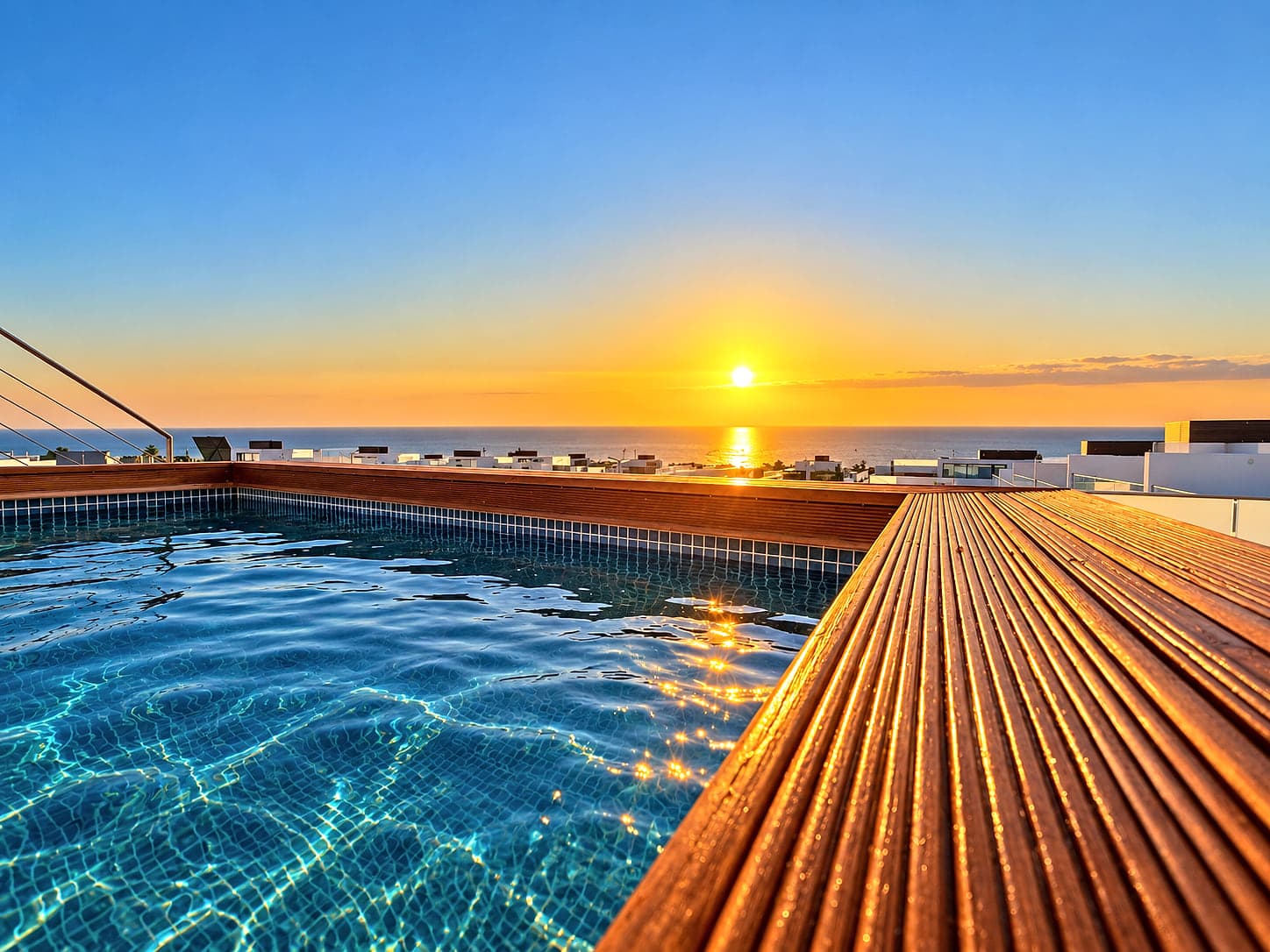 The private pool deck at Blue Cove, the sun setting over the sea beyond the rooftops