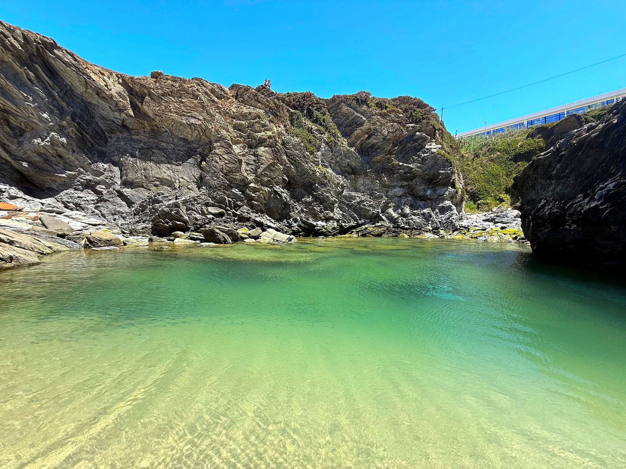 A tidal pool in the dark rock of the Porto Covo shoreline at low water